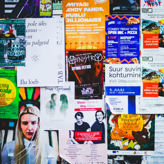 Collage of various colorful posters with different text and images on a wall.